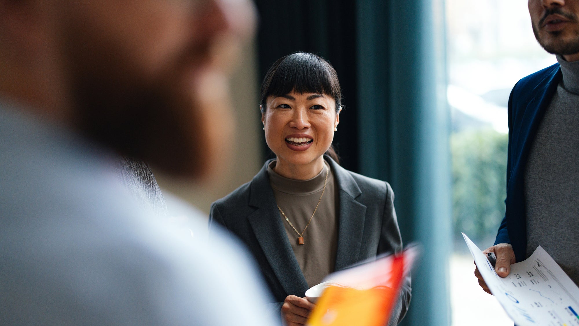 Une dame souriante dans un groupe de travail avec des documents dans la main