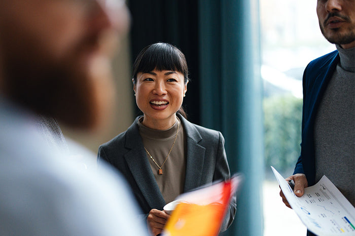 Une dame souriante dans un groupe de travail avec des documents dans la main