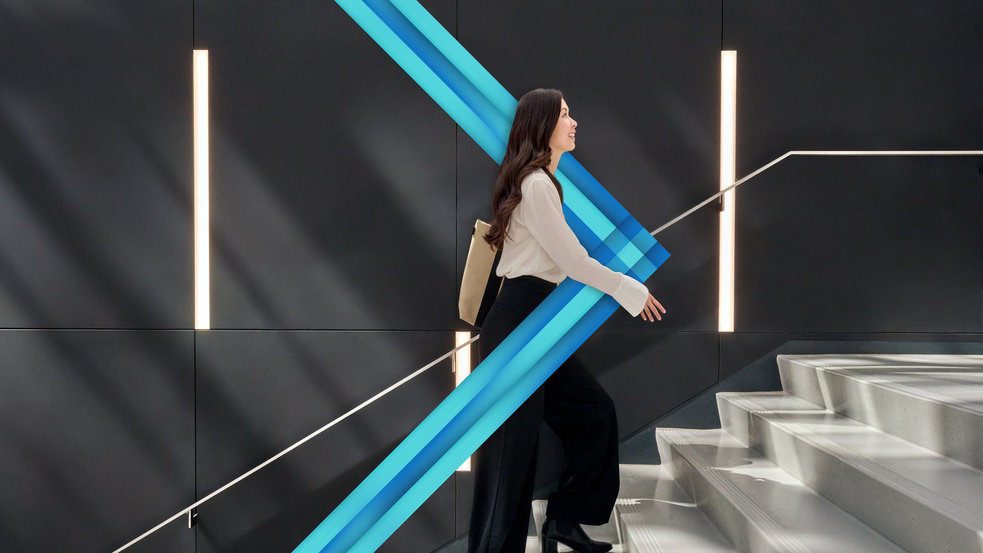 Femme montant un escalier, regard tourné vers le haut, portant un sac à main à l'épaule orné du chevron de l'École.