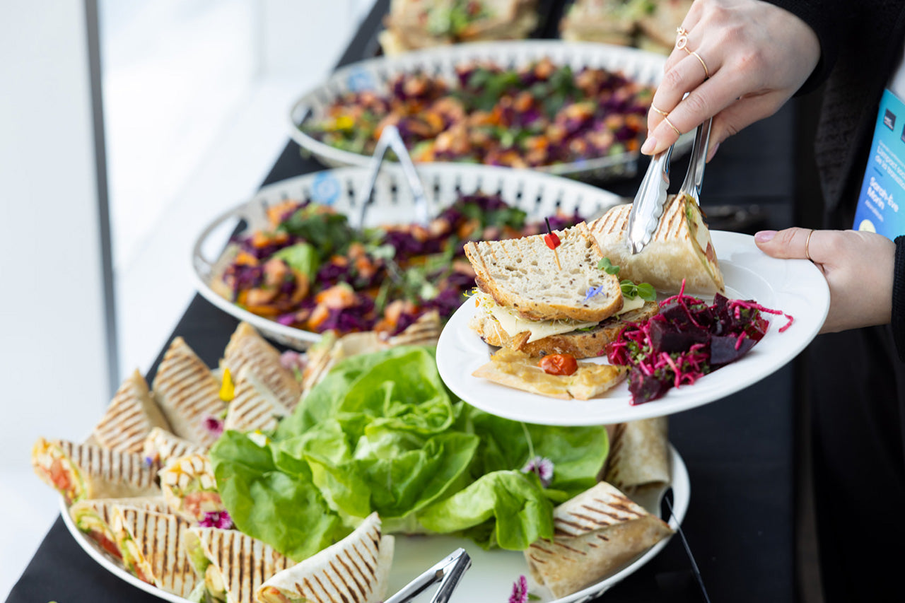 Buffet de sandwiches, salades et bouchées servi lors d’un événement avec service à l’assiette.